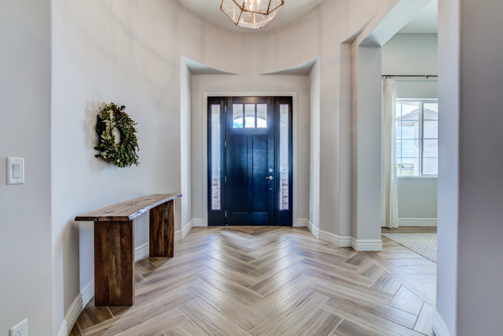 Photo of a large entry hall in Phoenix with beige walls, a pivot front door, brown floor and vaulted.