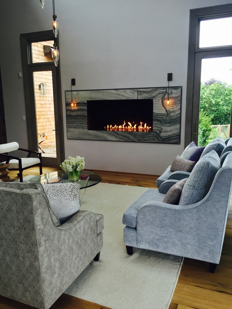 This is an example of a large modern formal open concept living room in New York with white walls, light hardwood floors, a standard fireplace and a stone fireplace surround.