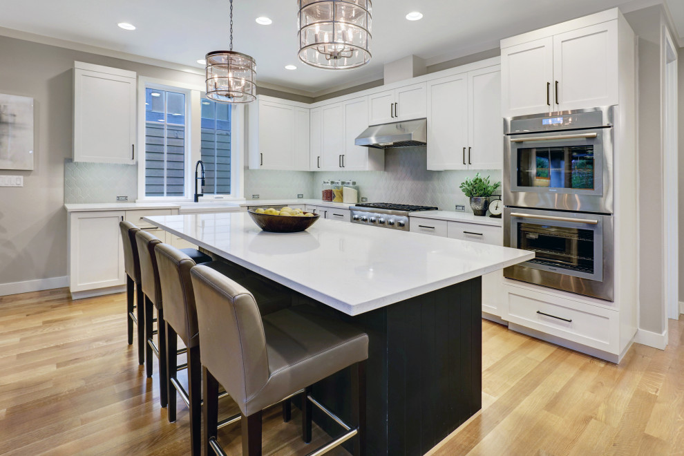 Example of a transitional l-shaped brown floor and light wood floor eat-in kitchen design in Seattle with a farmhouse sink, shaker cabinets, white cabinets, gray backsplash, stainless steel appliances, an island, quartzite countertops, ceramic backsplash and white countertops