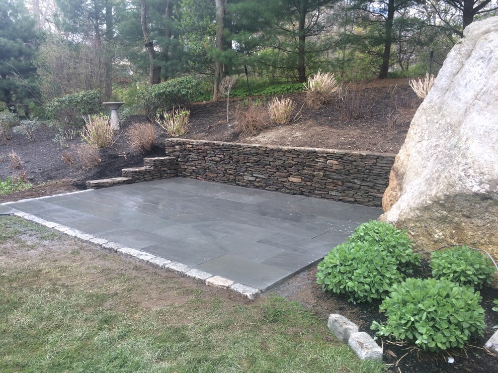 Inspiration for a mid-sized country backyard partial sun garden in Boston with a retaining wall and natural stone pavers.
