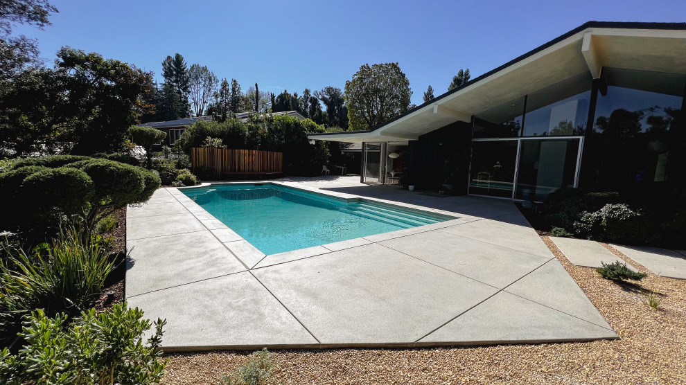 Inspiration for a mid-sized and desert look midcentury backyard full sun xeriscape for summer in Los Angeles with concrete pavers and a wood fence.