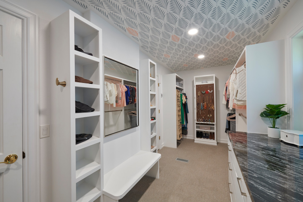На фото: гардеробная комната в классическом стиле с плоскими фасадами, белыми фасадами, ковровым покрытием, бежевым полом и потолком с обоями с