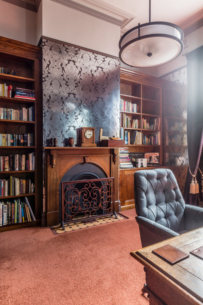 Mid-sized traditional study room in Melbourne with grey walls, carpet, a standard fireplace, a wood fireplace surround, a freestanding desk and orange floor.