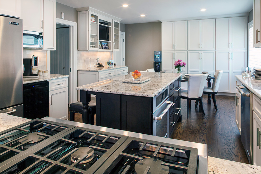 Inspiration for a large transitional galley dark wood floor eat-in kitchen remodel with an undermount sink, shaker cabinets, white cabinets, granite countertops, beige backsplash, stone tile backsplash, stainless steel appliances, brown walls and an island