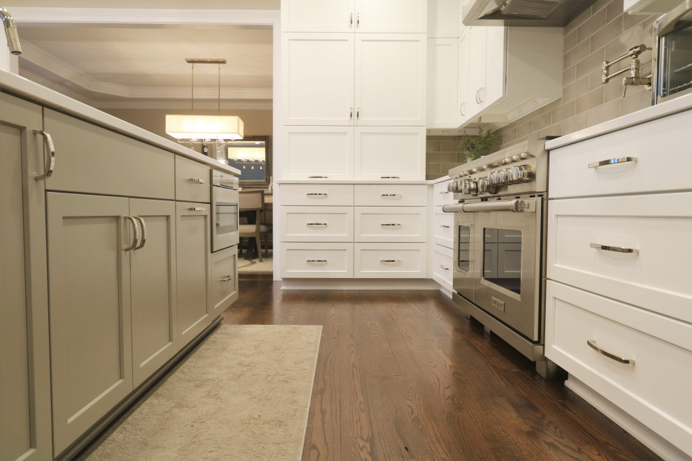 Example of a huge transitional u-shaped dark wood floor and brown floor eat-in kitchen design in Cincinnati with an undermount sink, recessed-panel cabinets, white cabinets, quartz countertops, beige backsplash, subway tile backsplash, stainless steel appliances, an island and white countertops