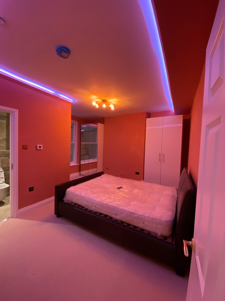 ロンドンにある中くらいなモダンスタイルのおしゃれな客用寝室 (青い壁、カーペット敷き、ベージュの床、格子天井、照明) のレイアウト