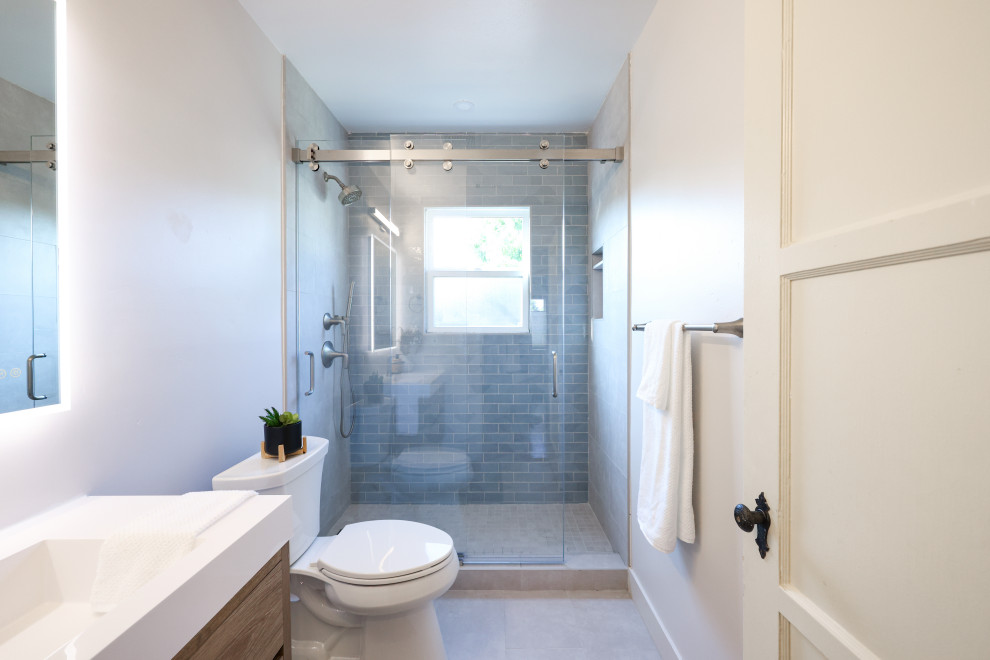 Идея дизайна: маленькая детская ванная комната в стиле модернизм с плоскими фасадами, светлыми деревянными фасадами, душем в нише, раздельным унитазом, синей плиткой, керамогранитной плиткой, белыми стенами, полом из керамогранита, врезной раковиной, столешницей из искусственного кварца, серым полом, белой столешницей, нишей, тумбой под одну раковину и подвесной тумбой для на участке и в саду