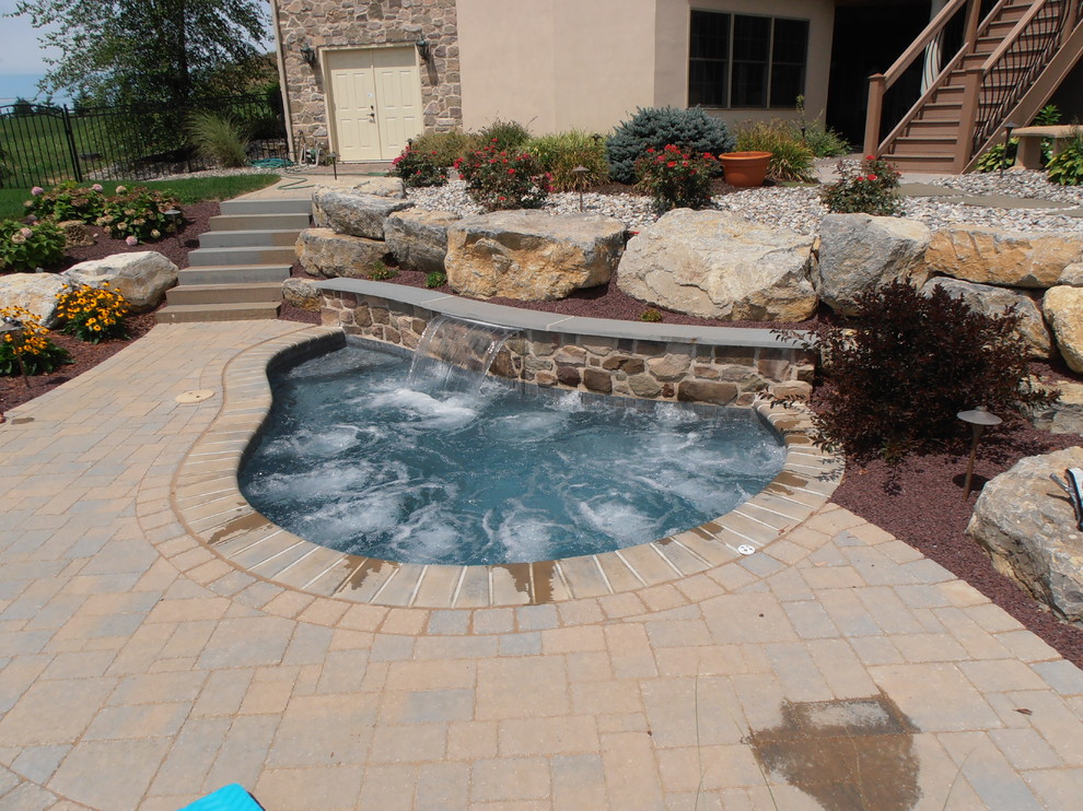 Photo of a traditional backyard custom-shaped natural pool in Philadelphia with a water slide and brick pavers.