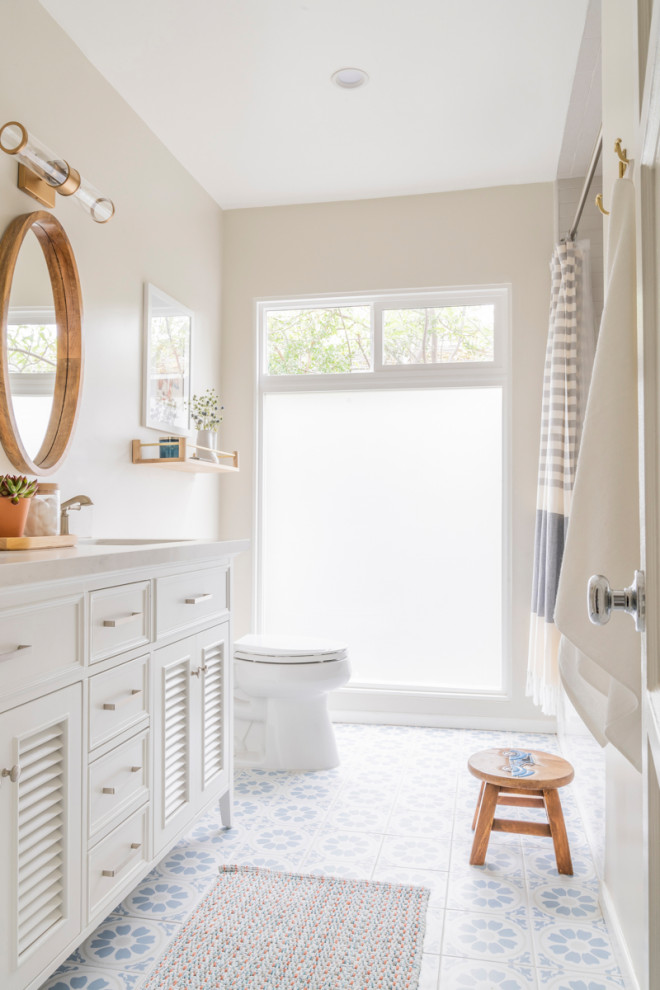 Design ideas for a transitional bathroom in Los Angeles with louvered cabinets, white cabinets, beige walls, an undermount sink, multi-coloured floor and beige benchtops.