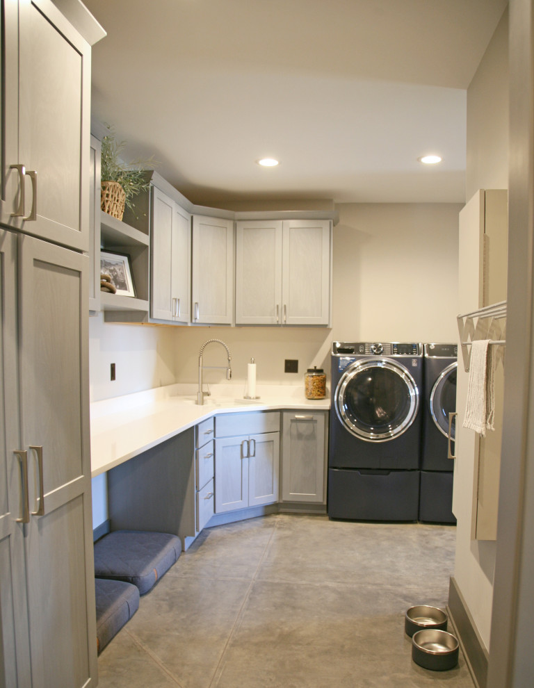 Mid-sized country l-shaped laundry room in Milwaukee with an undermount sink, shaker cabinets, distressed cabinets, quartz benchtops, beige walls, concrete floors, a side-by-side washer and dryer and white benchtop.