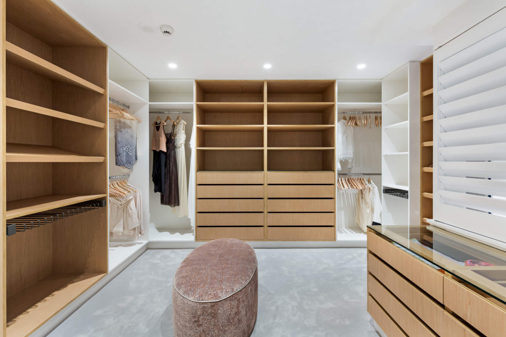 Design ideas for an expansive contemporary women's walk-in wardrobe in Sydney with open cabinets, light wood cabinets, carpet and grey floor.