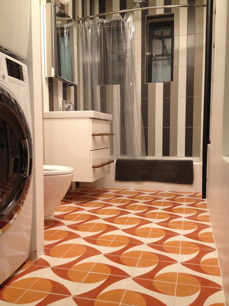 This is an example of a modern master bathroom in New York with a two-piece toilet, orange tile, cement tile and concrete floors.