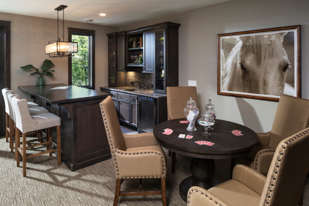 This is an example of a mid-sized traditional galley seated home bar in Minneapolis with an undermount sink, granite benchtops, carpet, recessed-panel cabinets, dark wood cabinets, brown splashback and brown floor.