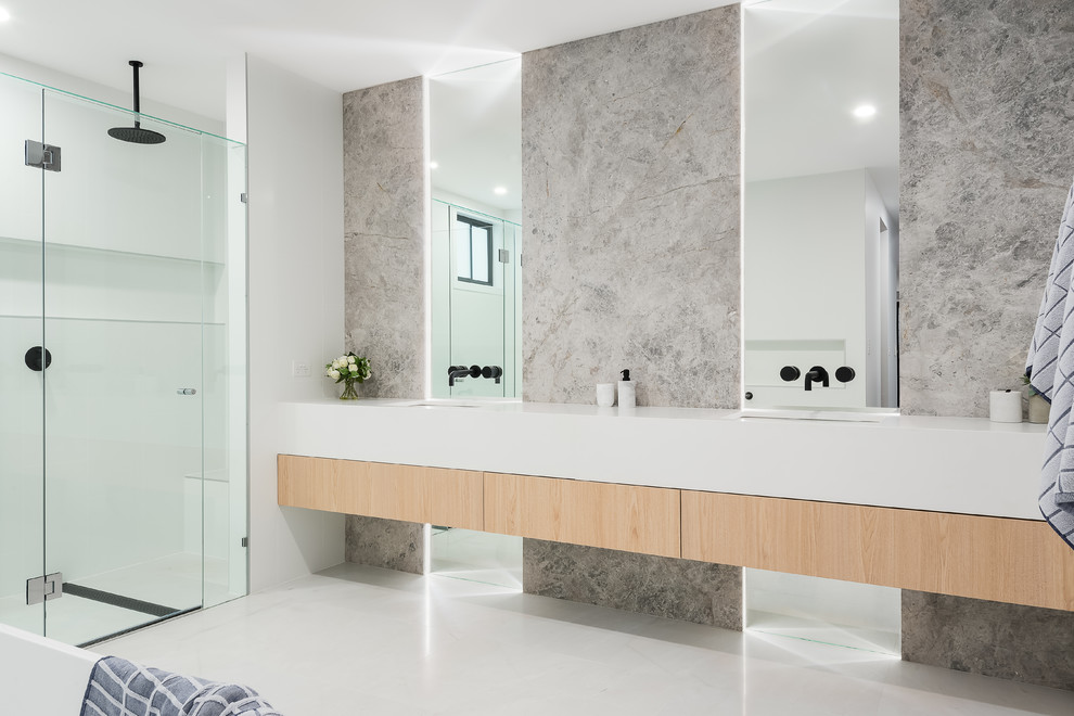 Inspiration for an expansive contemporary master bathroom in Brisbane with light wood cabinets, a freestanding tub, a shower/bathtub combo, gray tile, marble, white walls, marble floors, an undermount sink, engineered quartz benchtops, white floor, white benchtops, flat-panel cabinets and a hinged shower door.