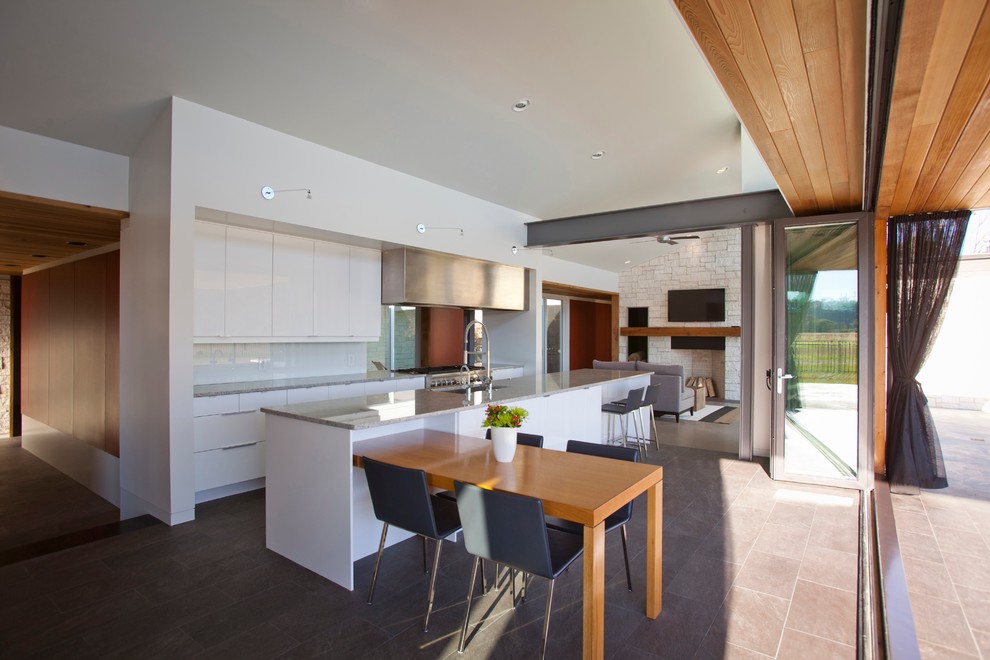 Inspiration for a modern single-wall open concept kitchen remodel in Cincinnati with a single-bowl sink, flat-panel cabinets, white cabinets, granite countertops, white backsplash, glass sheet backsplash and stainless steel appliances