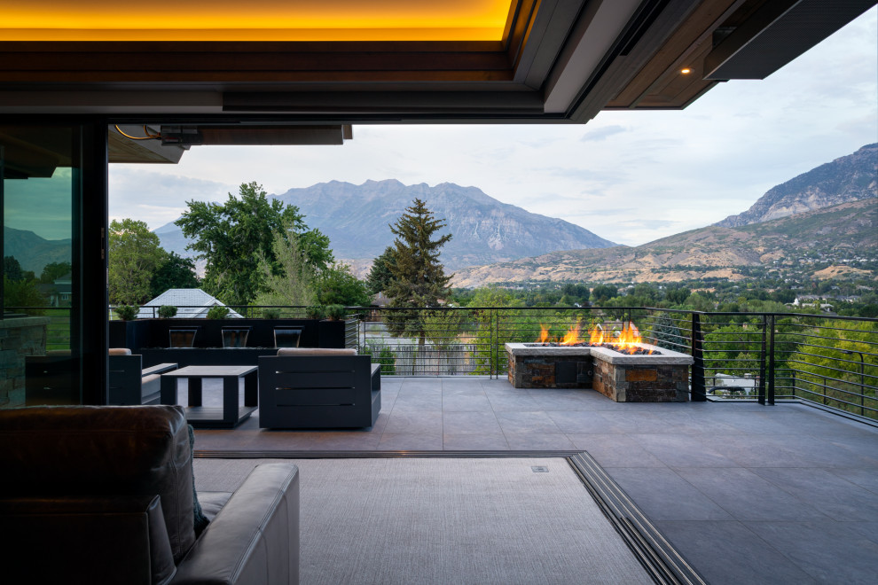 Photo of a large world-inspired roof first floor metal railing terrace in Salt Lake City with a fire feature and a roof extension.