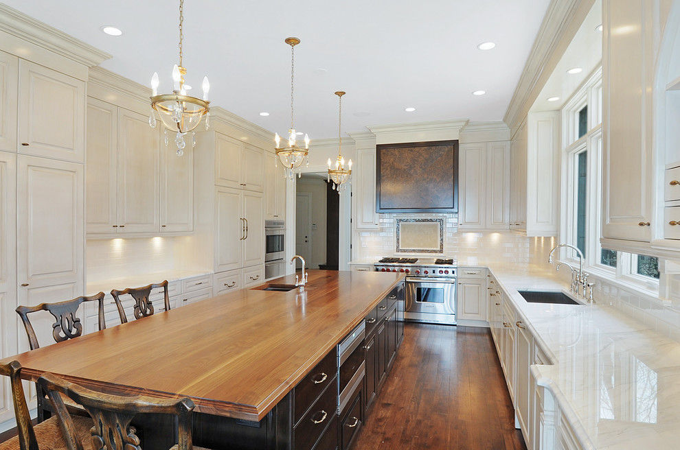 Inspiration for a large traditional u-shaped open plan kitchen in Chicago with an undermount sink, raised-panel cabinets, beige cabinets, wood benchtops, white splashback, porcelain splashback, panelled appliances, dark hardwood floors, with island and brown floor.