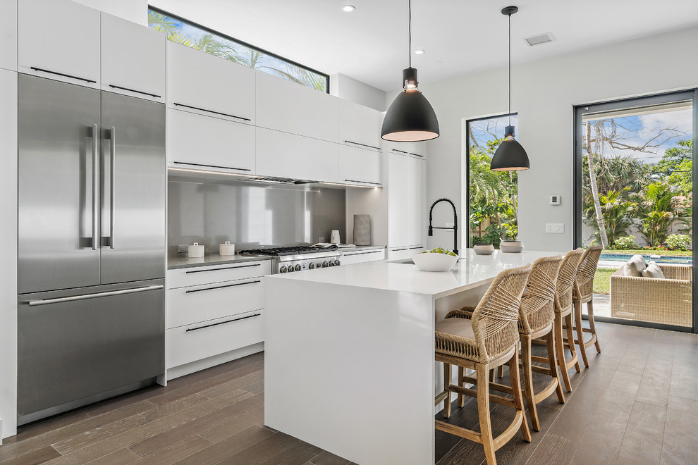 Inspiration for a contemporary kitchen in Miami with an undermount sink, flat-panel cabinets, white cabinets, grey splashback, glass sheet splashback, stainless steel appliances, dark hardwood floors, with island, brown floor and grey benchtop.