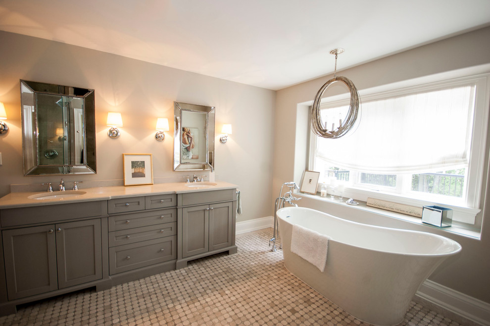This is an example of a large transitional master bathroom in Toronto with shaker cabinets, grey cabinets, a freestanding tub, beige tile, quartzite benchtops, a one-piece toilet, beige walls, mosaic tile floors and an undermount sink.
