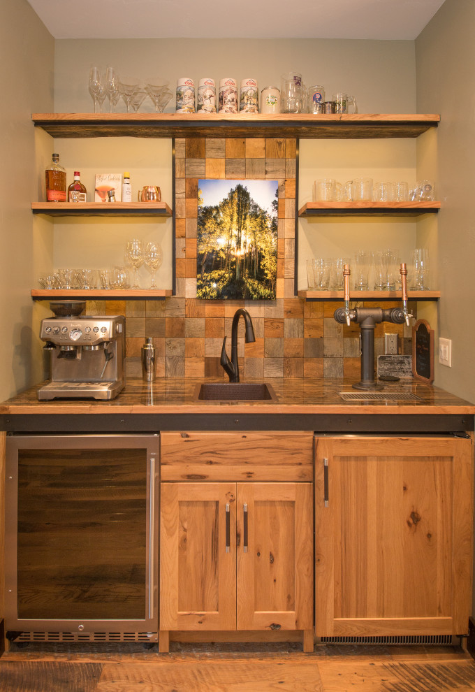 Photo of a country single-wall wet bar in Other with a drop-in sink, shaker cabinets, medium wood cabinets, brown splashback, medium hardwood floors and brown floor.
