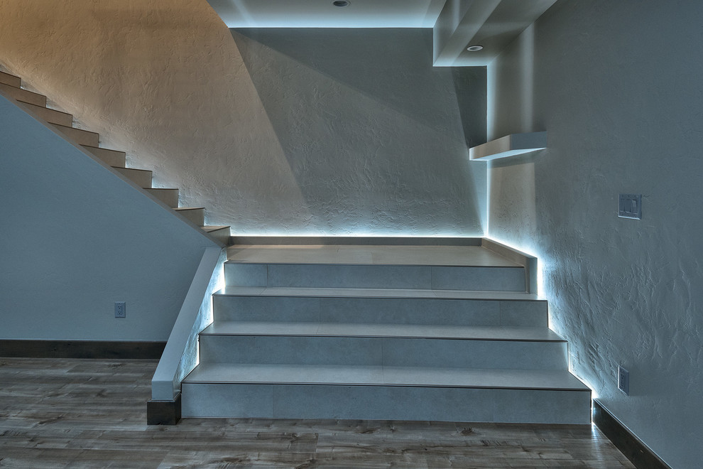 This is an example of a large modern tile l-shaped staircase in Denver with tile risers.