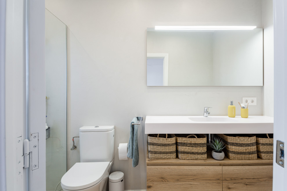 This is an example of a mid-sized scandinavian 3/4 bathroom in Other with flat-panel cabinets, white cabinets, a curbless shower, beige tile, beige walls, laminate floors, an integrated sink, beige floor, white benchtops and a single vanity.