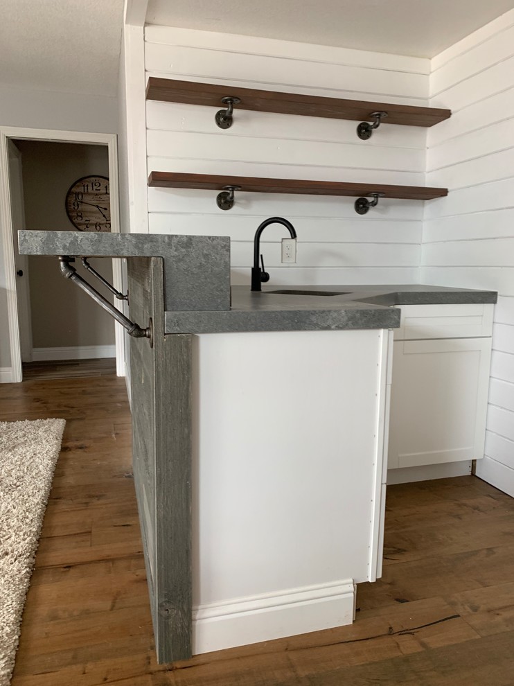 Photo of a small industrial l-shaped wet bar in Sacramento with an undermount sink, quartz benchtops, dark hardwood floors, brown floor and grey benchtop.