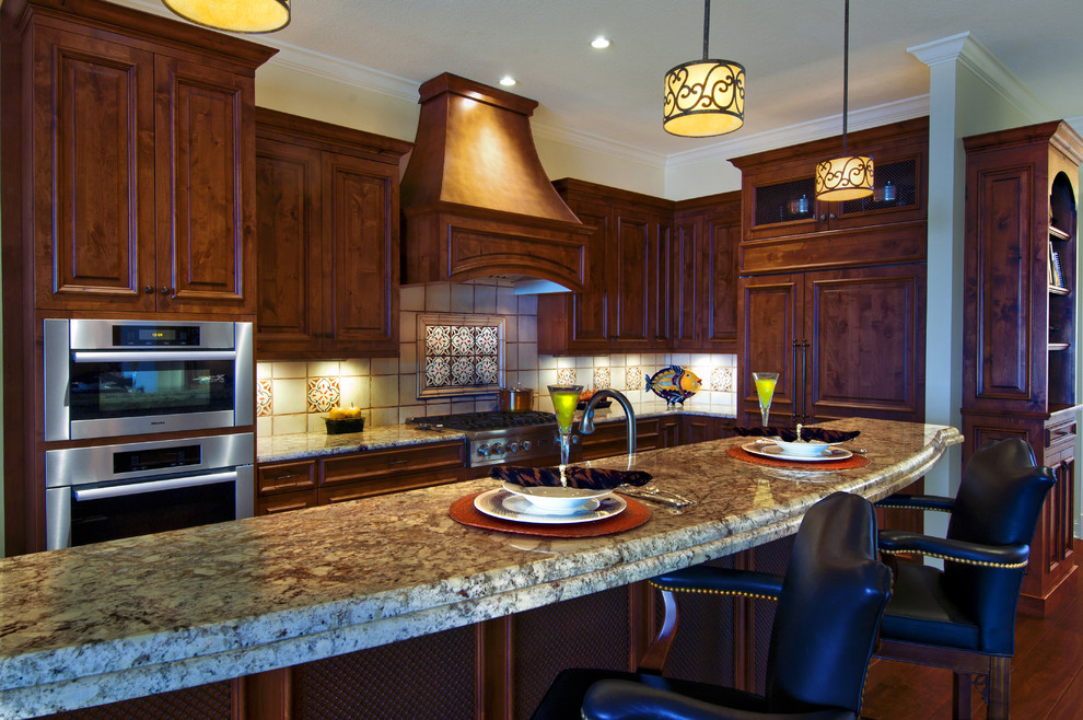 Photo of a large traditional l-shaped separate kitchen in Tampa with an undermount sink, raised-panel cabinets, dark wood cabinets, granite benchtops, beige splashback, ceramic splashback, stainless steel appliances, dark hardwood floors, with island, brown floor and beige benchtop.