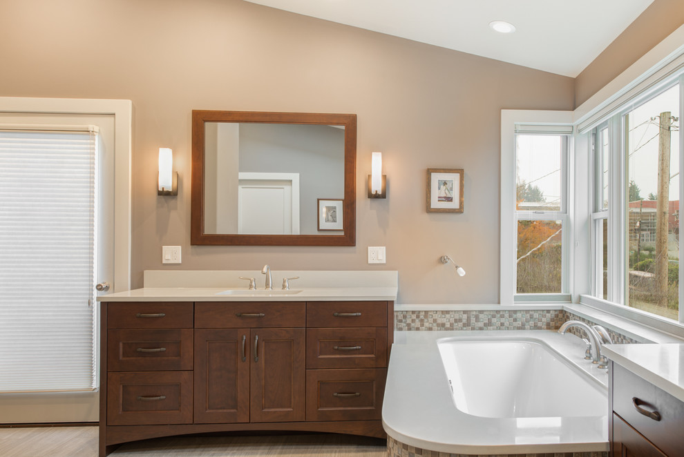 Inspiration for a large transitional master bathroom in Seattle with recessed-panel cabinets, medium wood cabinets, a corner tub, an alcove shower, a two-piece toilet, multi-coloured tile, ceramic tile, beige walls, an undermount sink and engineered quartz benchtops.