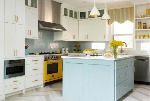 Kid-friendly kitchen with a light-blue island and low drawers within children’s reach, paired with white cabinets and a yellow range