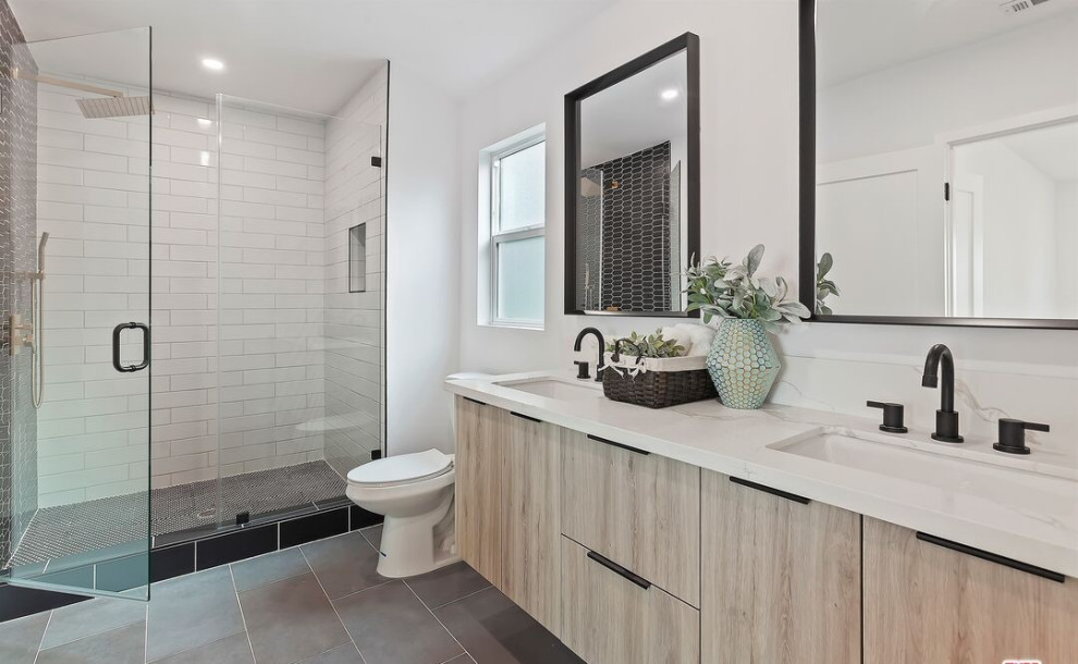 This is an example of a contemporary bathroom in Los Angeles with flat-panel cabinets, light wood cabinets, an alcove shower, a one-piece toilet, white tile, ceramic tile, white walls, ceramic floors, an undermount sink, engineered quartz benchtops, grey floor, a hinged shower door, white benchtops, a niche, a single vanity and a floating vanity.