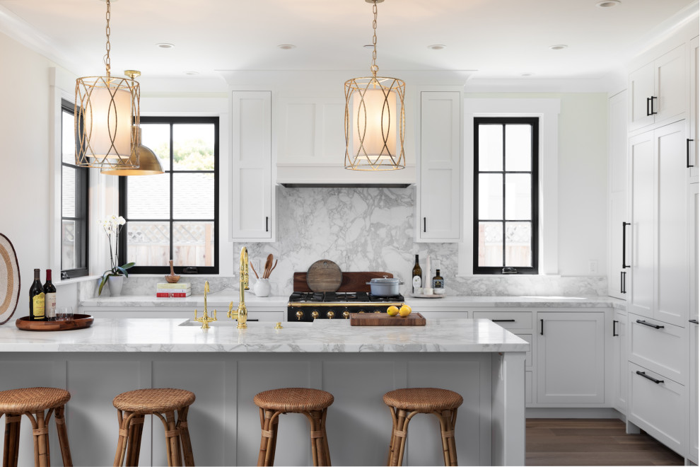 Mid-sized beach style l-shaped medium tone wood floor and beige floor eat-in kitchen photo in Other with a farmhouse sink, recessed-panel cabinets, white cabinets, marble countertops, white backsplash, marble backsplash, paneled appliances, a peninsula and white countertops