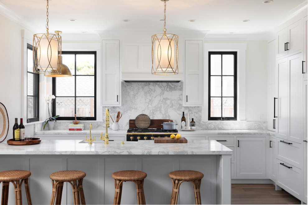 Mid-sized beach style l-shaped medium tone wood floor and beige floor eat-in kitchen photo with a farmhouse sink, recessed-panel cabinets, white cabinets, marble countertops, white backsplash, marble backsplash, paneled appliances, a peninsula and white countertops