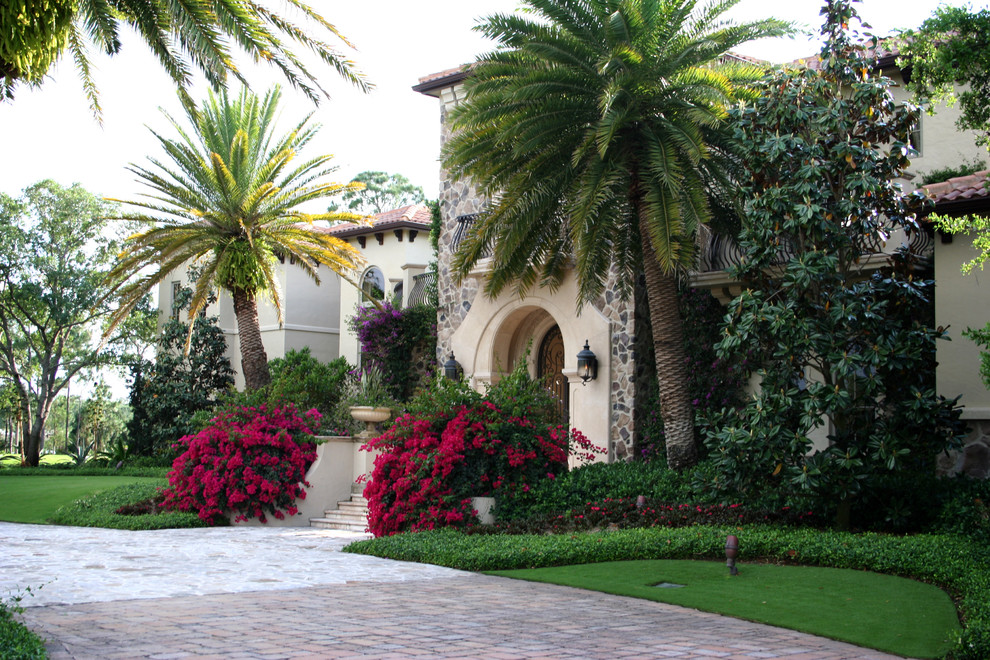 Inspiration for an expansive traditional front yard partial sun driveway for spring in Miami with a garden path and natural stone pavers.