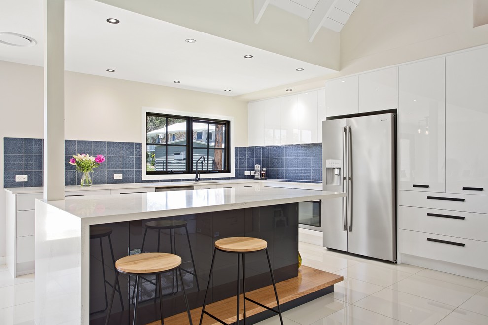 Design ideas for a contemporary l-shaped kitchen in Gold Coast - Tweed with an undermount sink, flat-panel cabinets, white cabinets, blue splashback, stainless steel appliances, with island and white floor.