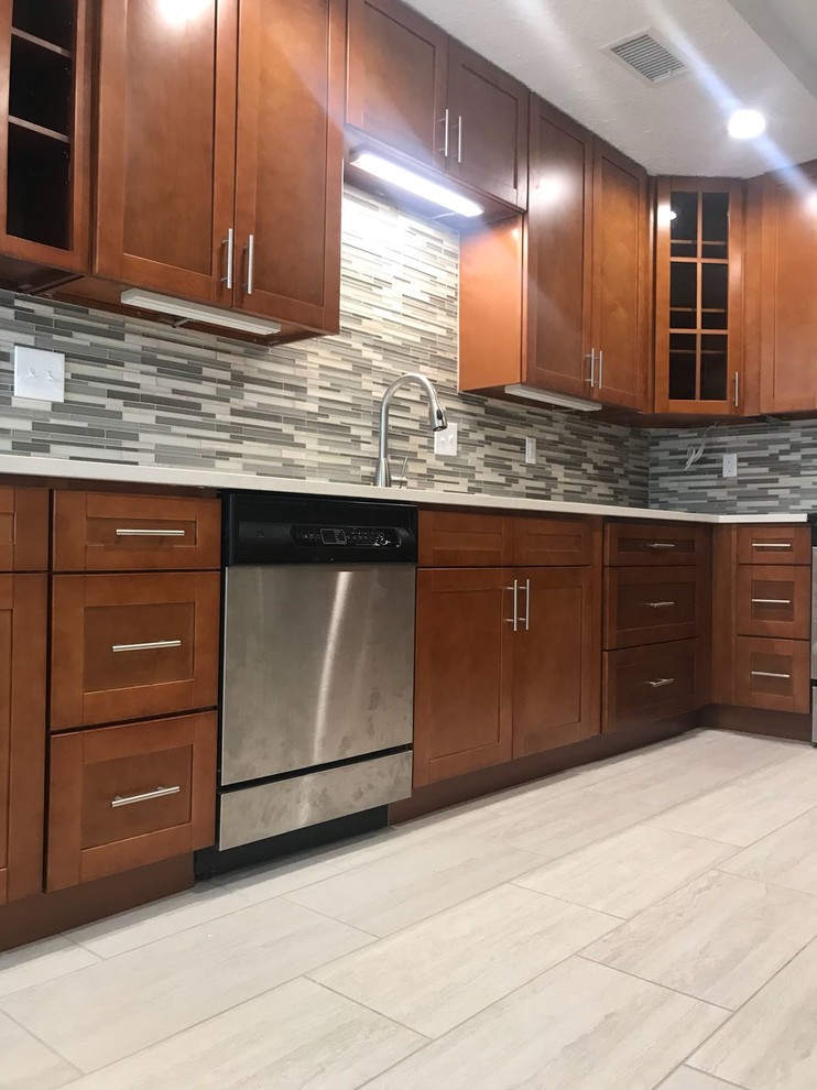 Enclosed kitchen - mid-sized transitional u-shaped porcelain tile and gray floor enclosed kitchen idea in Houston with an undermount sink, shaker cabinets, medium tone wood cabinets, quartz countertops, multicolored backsplash, glass tile backsplash, stainless steel appliances, no island and white countertops