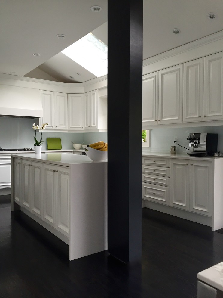 Inspiration för små moderna kök, med en dubbel diskho, luckor med upphöjd panel, vita skåp, bänkskiva i kvarts, glaspanel som stänkskydd, mörkt trägolv, en köksö, vitt stänkskydd och svarta vitvaror