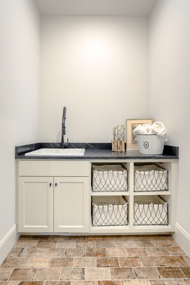 Esempio di una sala lavanderia classica con lavatoio, ante in stile shaker, ante bianche, top in granito, pavimento in mattoni, lavatrice e asciugatrice affiancate e top nero