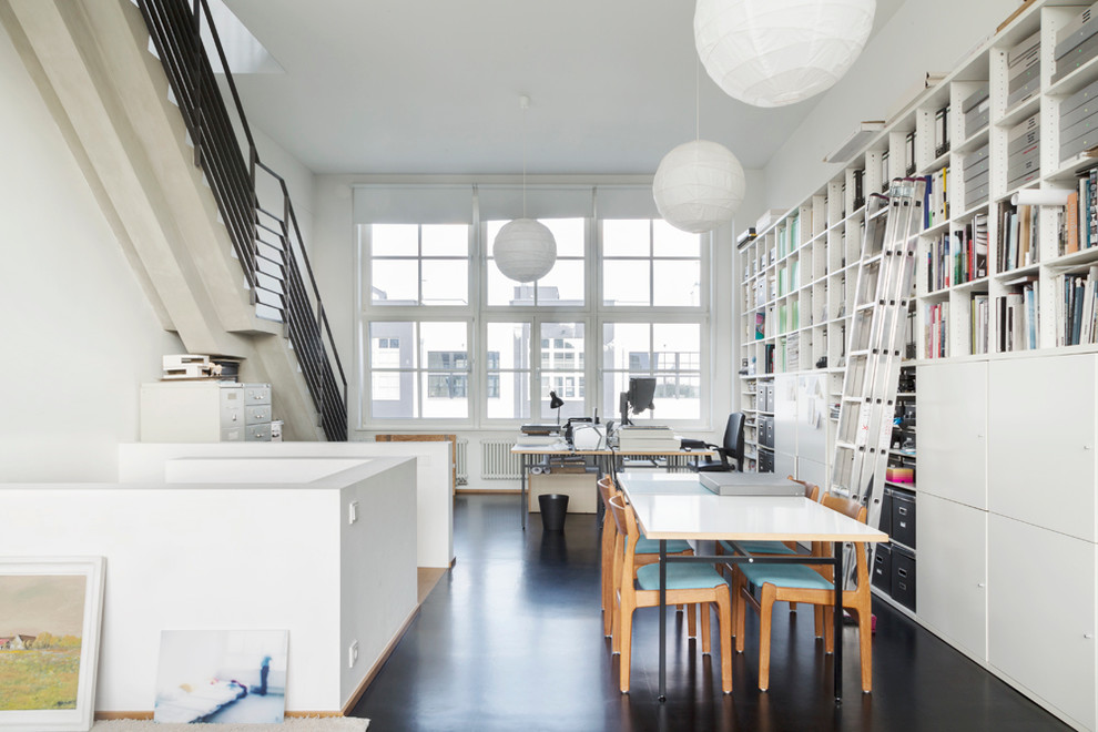 Inspiration for a mid-sized industrial home office in Berlin with a library, white walls and no fireplace.