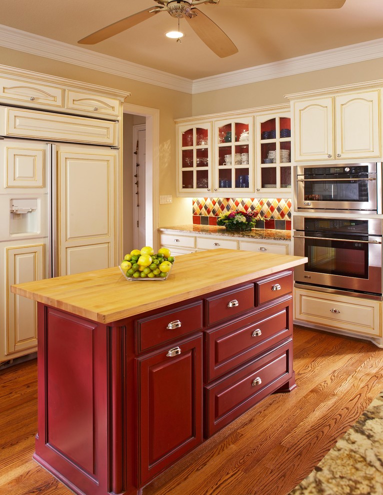This is an example of a traditional kitchen in Dallas with glass-front cabinets, wood benchtops and red cabinets.