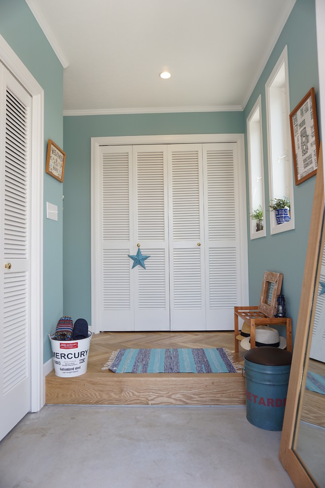 This is an example of a tropical entryway in Other with blue walls and concrete floors.