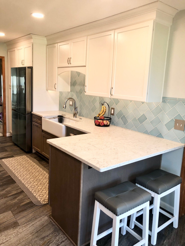 Enclosed kitchen - mid-sized farmhouse u-shaped vinyl floor and gray floor enclosed kitchen idea in Detroit with a farmhouse sink, flat-panel cabinets, medium tone wood cabinets, quartz countertops, blue backsplash, ceramic backsplash, stainless steel appliances, a peninsula and white countertops