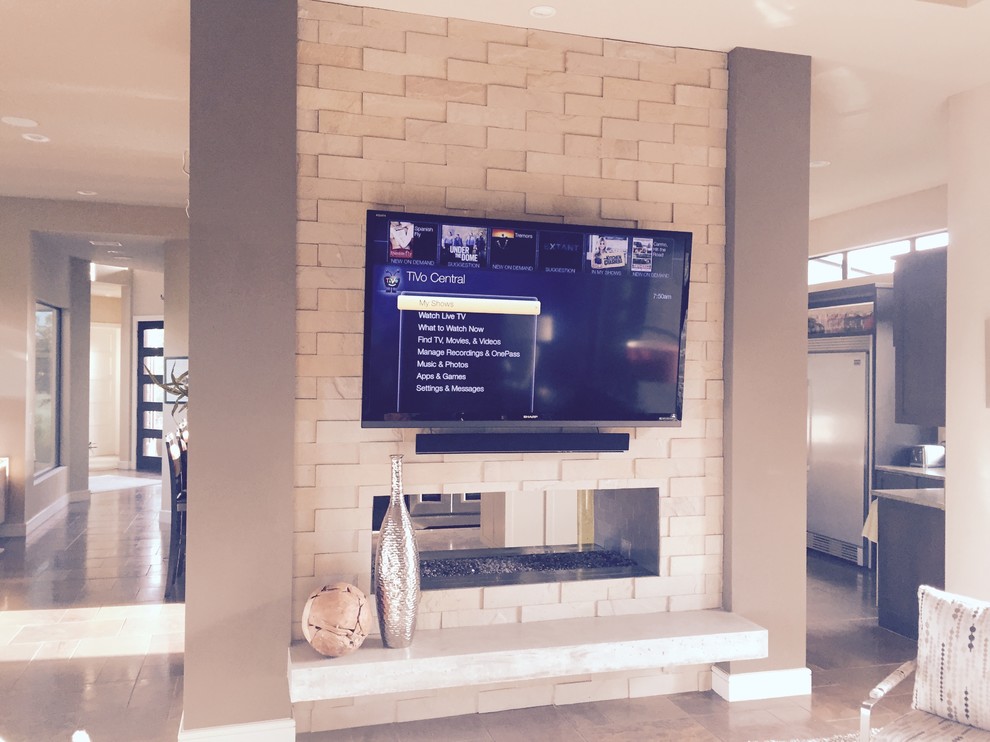 Photo of a mid-sized contemporary open concept family room in Austin with grey walls, a two-sided fireplace, a stone fireplace surround and a wall-mounted tv.