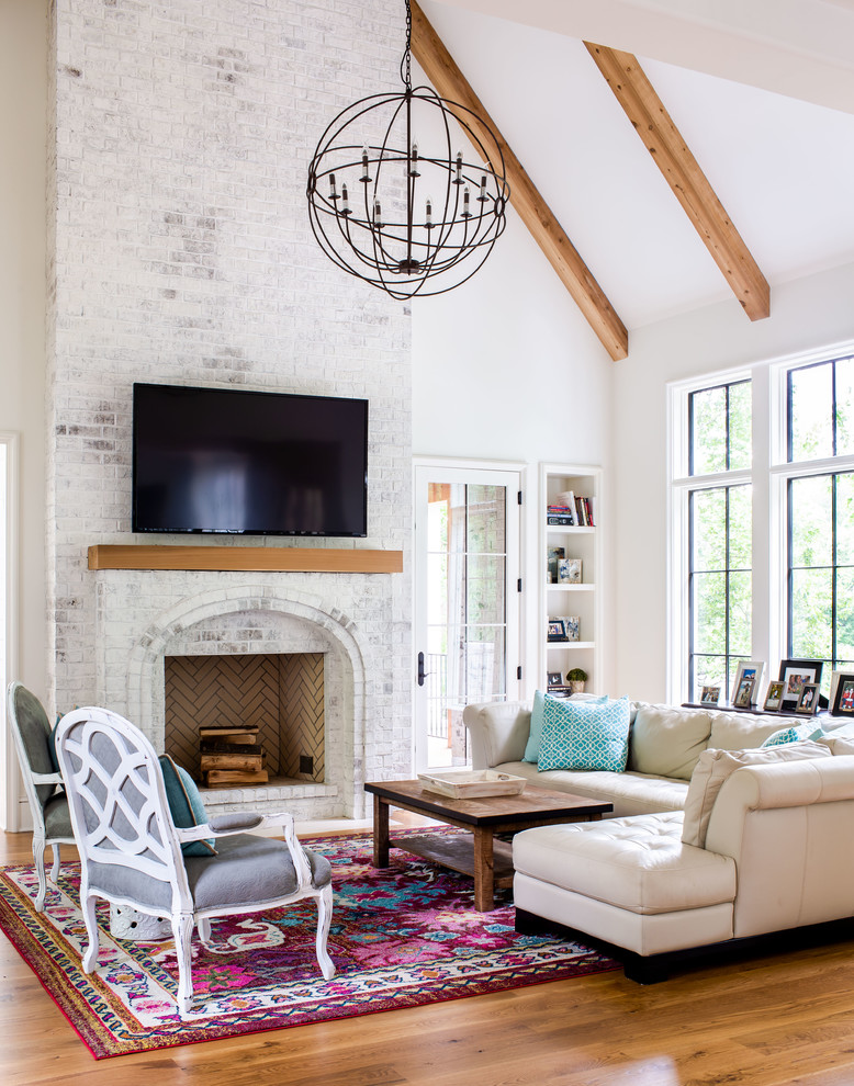 Design ideas for a transitional living room in Atlanta with a library, white walls, medium hardwood floors, a standard fireplace, a wall-mounted tv and brown floor.