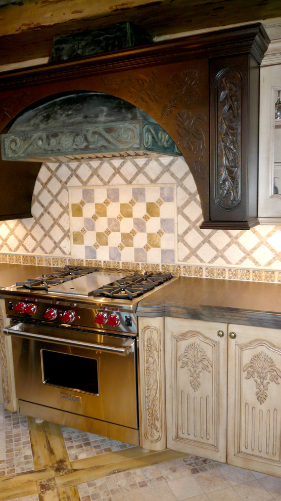 Example of an eclectic kitchen design in Phoenix with beige backsplash, stone tile backsplash, stainless steel appliances and an island