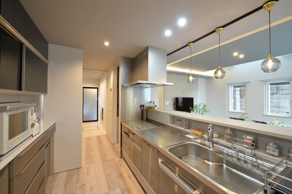 This is an example of a modern single-wall open plan kitchen in Other with an integrated sink, flat-panel cabinets, painted wood floors, a peninsula and beige floor.