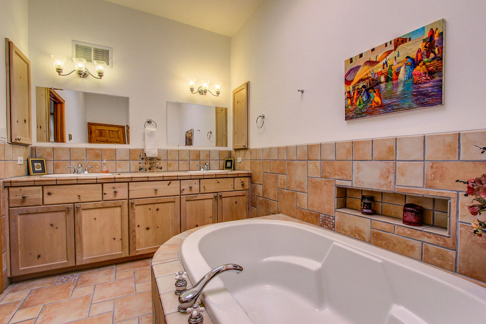 Photo of a large contemporary master bathroom in Albuquerque with a drop-in sink, shaker cabinets, light wood cabinets, tile benchtops, a drop-in tub, a corner shower, a two-piece toilet, beige tile, terra-cotta tile, white walls and terra-cotta floors.