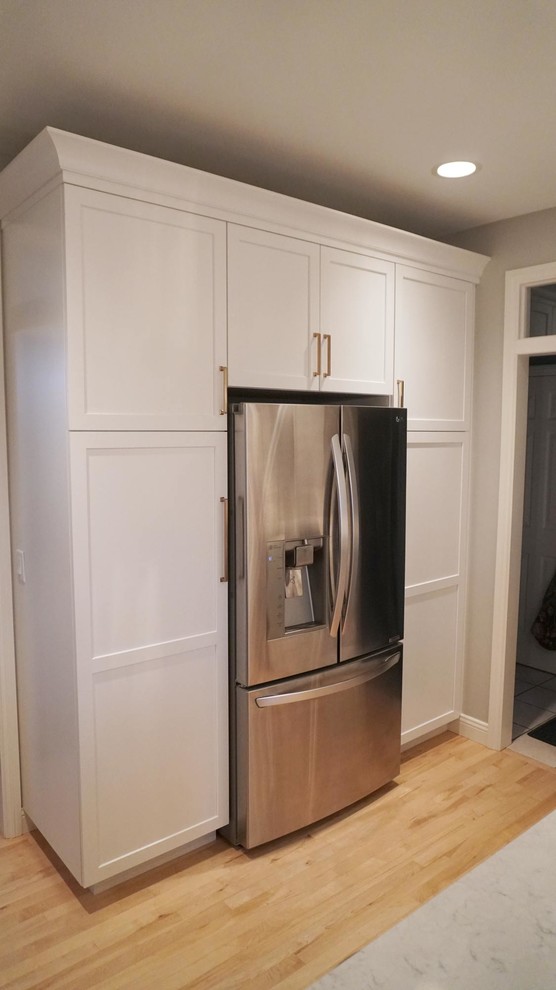 Open concept kitchen - transitional light wood floor open concept kitchen idea with a farmhouse sink, recessed-panel cabinets, white cabinets, white backsplash, subway tile backsplash, stainless steel appliances, an island and white countertops