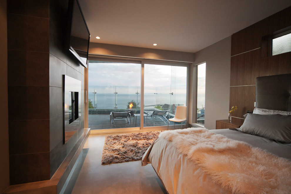 Design ideas for a modern bedroom in Vancouver with beige walls, a standard fireplace and a metal fireplace surround.