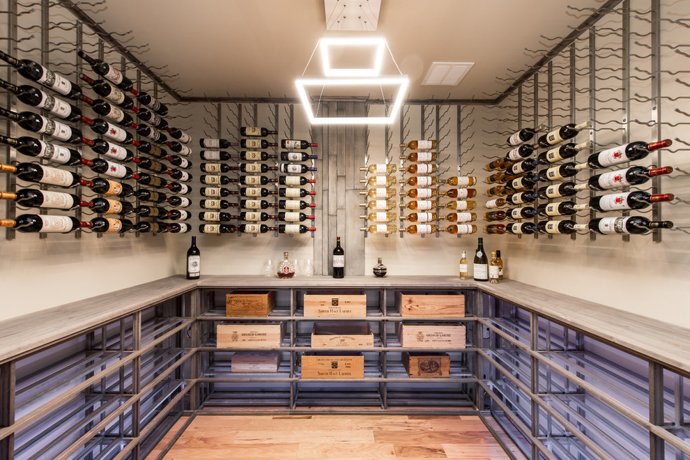 Photo of an industrial wine cellar in Denver with medium hardwood floors, display racks and brown floor.